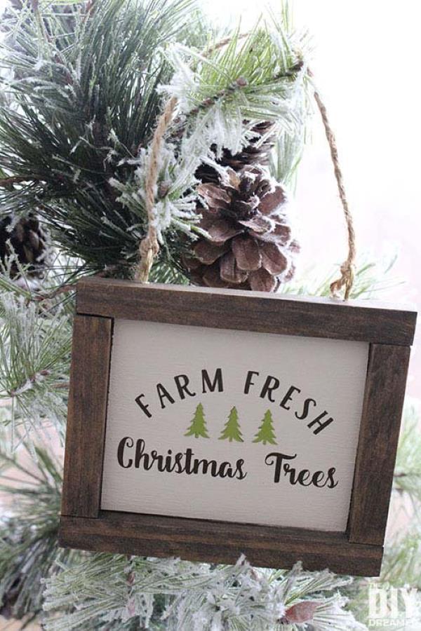 Wood framed sign with "farm fresh christmas trees" written on it, hanging on the tree