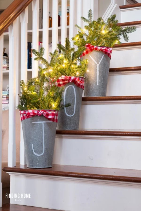 3 planters that spell "JOY" with pine tree branches in them