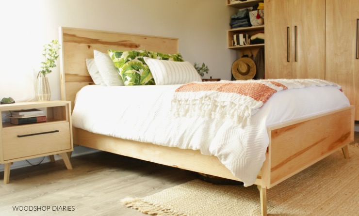 a simple midcentury bed frame with a plywood head and footboards in a natural, unfinished wood look